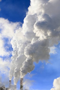 Mavi gökyüzüne karşı bitkinin bacasından izole edilmiş beyaz duman.
