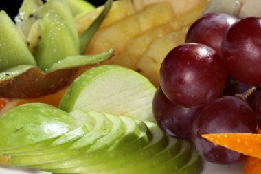 Siyah arka plan stüdyosunda beyaz tabakta güzel bir meyve salatası.