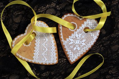 Siyah arka plan stüdyosuna asılmış sarı bantlı kalp şeklinde zencefilli paskalya pastası.