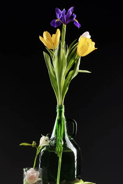 Close Beautiful Tulips Irises Glass Bottle Black Background Studio — Stock Photo, Image