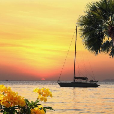 Deniz manzaralı gün batımı ve Tayland kıyılarında sönük yelkenli bir tekne.