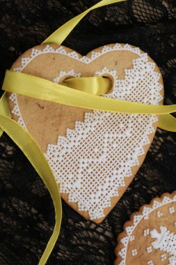 Siyah arka plan stüdyosuna asılmış sarı bantlı kalp şeklinde zencefilli paskalya pastası.