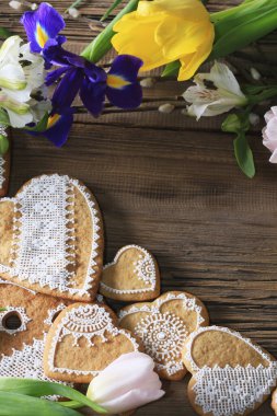  Sarı kurdeleli kalp şeklinde makro zencefilli kurabiye, ahşap arka planda çiçekler.