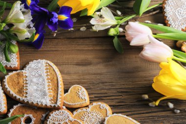  Sarı kurdeleli kalp şeklinde makro zencefilli kurabiye, ahşap arka planda çiçekler.