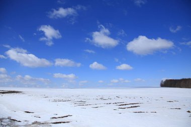 ilkbahar karları erir tarlada ve beyaz bulutlar mavi gökyüzünde güneşli bir günde