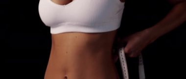 Sıska spor kızı beyaz iç çamaşırlarıyla solda siyah arkaplan metin alanı olan göğüs ölçüleri alıyor.