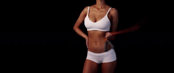 Slank gebruinde vrouw in wit ondergoed blijft springtouw in handen op de zwarte achtergrond componeren met tekstruimte — Stockvideo