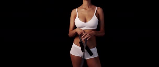 Femme mince bronzée en sous-vêtements blancs continue à sauter corde dans les mains sur le fond noir composer avec l'espace de texte — Video
