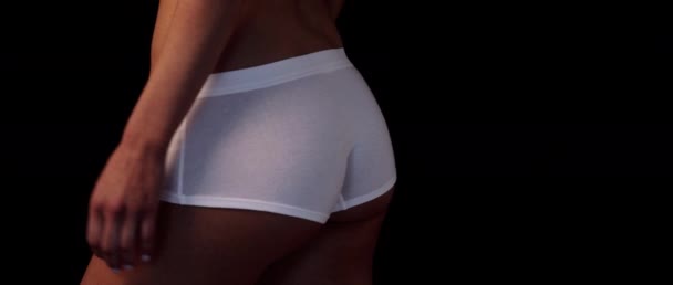 Schlankes Sportmädchen mit gebräuntem Körper in weißer Unterwäsche misst Hüften mit schwarzem Hintergrund rechts — Stockvideo