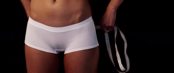 Slim sport girl back tanned body in white underwear doing measures hips with the black background text space to the right — Stock Video