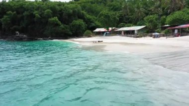 Kar beyazı bir plajda uzanan bir kız, dalgaları yakalar ve güzel doğayla çevrili güneşin ışınlarından zevk alır.