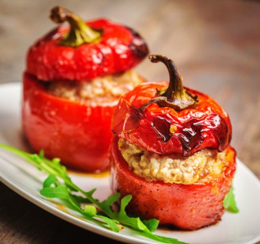 Ahşap masa üzerinde beyaz tabak etli biber dolması