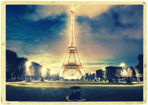 Casal olhando para a Torre Eiffel à noite — Fotografia de Stock