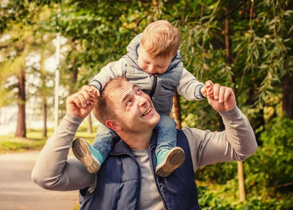 Pojken sitter på halsen på far — Stockfoto