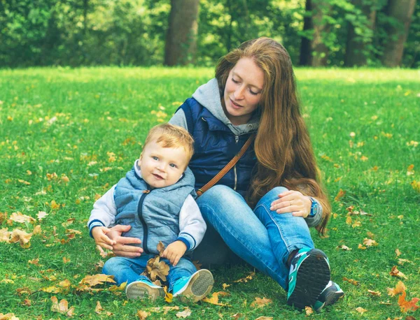 Moeder met zoon zit op gras — Stockfoto