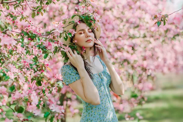 Mavi elbiseli ve hasır şapkalı güzel bir genç kız çiçek açan bahçede rüya görüyor.