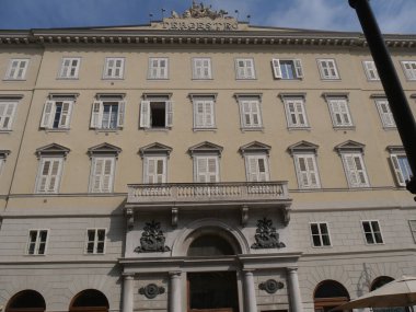 Trieste 'deki Tergesteo binası, neoklasik stili ve cephede egemen olan mermer heykeli ile harici.