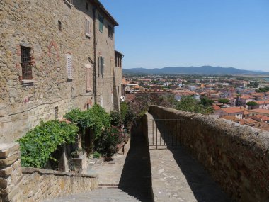 Typical medieval street to the top of Castiglione della Pescaia, squeezed between the walkway of the walls and the houses covered with vegetation.