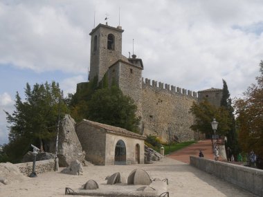 San Marino, Birinci Kule. Kalenin ön tarafı büyük taş duvarlarla çevrili, çan kulesi ve asma köprü olan giriş kapısı.