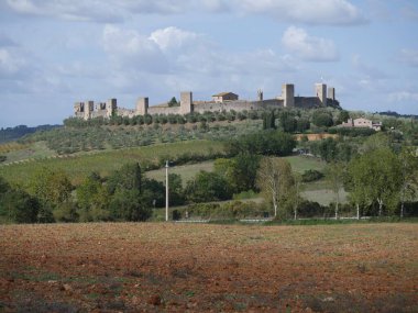 Monteriggioni Kalesi 'nin panorama' sı. Etrafı kırsal ve zeytinliklerle çevrili bir tepenin tepesinde 14 kuleli dairesel çevre duvarları var.
