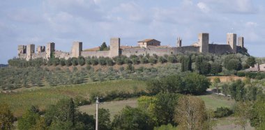Monteriggioni Kalesi 'nin panorama' sı. Etrafı kırsal ve zeytinliklerle çevrili bir tepenin tepesinde 14 kuleli dairesel çevre duvarları var.
