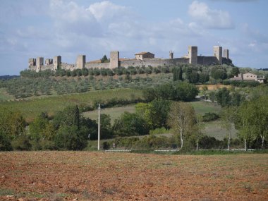 Monteriggioni Kalesi 'nin panorama' sı. Etrafı kırsal ve zeytinliklerle çevrili bir tepenin tepesinde 14 kuleli dairesel çevre duvarları var.