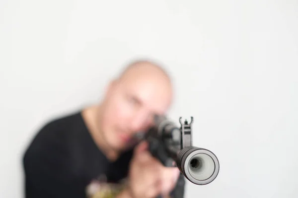 Heavy blurred man on light background with rifle in hands