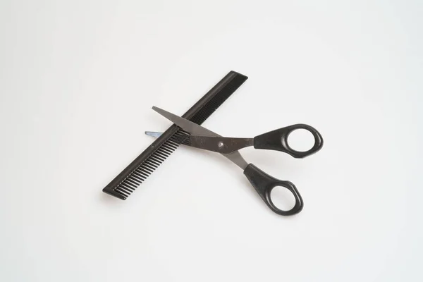 Nerezové nůžky s černou rukojetí leží a hřeben na lehkém stole — Stock fotografie