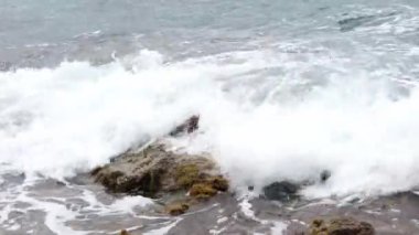 Deniz dalgaları kıyıya yakın kayalara çarpıyor.