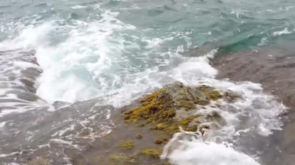 Tengerhullámok zuhannak le sziklákon a partvonal közelében — Stock videók