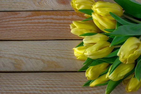 Ramo de tulipanes amarillos sobre una mesa de madera —  Fotos de Stock