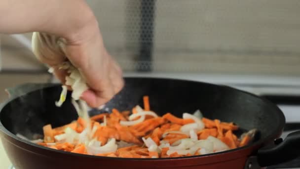 Homme mettant l'oignon dans la casserole sur la cuisinière 