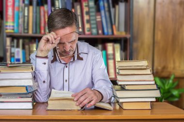 kitaplarla dolu masasında oturan adam 