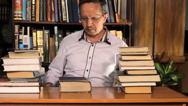 Hombre estudiando entre los libros — Vídeos de Stock