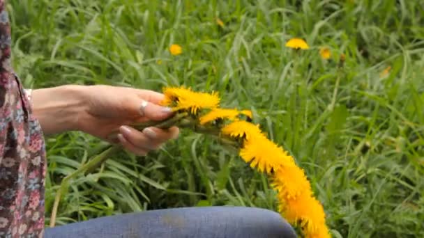 Woman weaves a wreath of dandelions — Stock Video