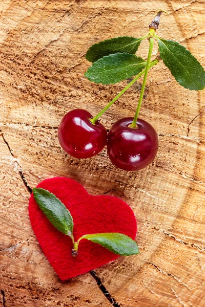 Cherry and red heart on a wooden table — Stock Photo, Image