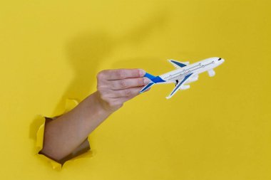 Yırtık sarı kağıt üzerinde el ele tutuşan uçak. Turizm ve yaz tatili kavramları