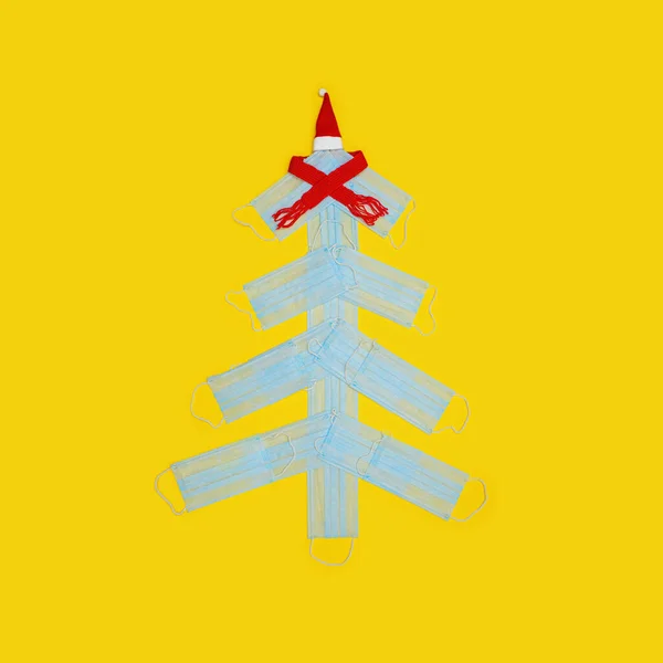 Árbol de Navidad hecho de mascarillas médicas sobre papel amarillo. Concepto de Coronavirus — Foto de Stock