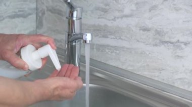 Adam ellerini sabunla yıkıyor. Evdeki sokakların altında. Sağlık, temizlik, mikrop ve koronavirüsün ellerle temas etmesini önlemek. 4k görüntü