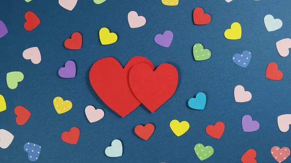 休日の概要多色の紙のハートでバレンタインの背景。青い背景に切り取られた紙の心 — ストック写真