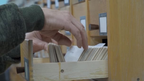 Una mano masculina buscando tarjetas en el viejo catálogo de tarjetas de madera. — Vídeos de Stock