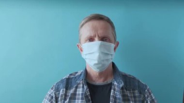 Yakışıklı kıdemli adam yüzünde tıbbi maskeyi çıkarıp gülüyor..