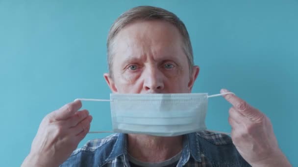 Hombre mayor guapo poniendo máscara médica en la cara — Vídeos de Stock
