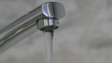 Krom kaplamalı musluktan akan su akışı. 4K çözünürlüğü