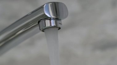 Krom kaplamalı musluktan akan su akışı. 4K çözünürlüğü