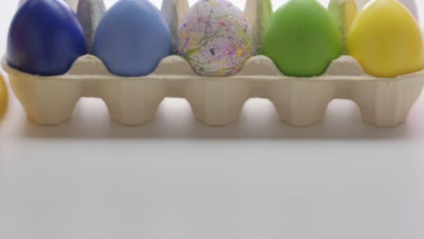 Великодні барвисті яйця катаються на білому столі. Традиційна весняна композиція. 4k відео . — стокове відео