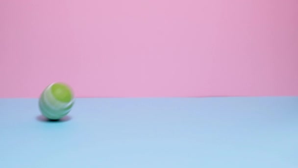 Coloré peint oeufs de Pâques rouler et frapper sur un fond bleu et rose. — Video