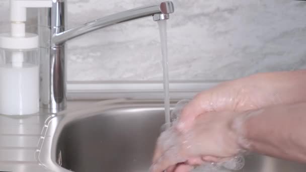 Руки человека моют руки в раковине с пеной, чтобы вымыть кожу и вода течет через руки — стоковое видео