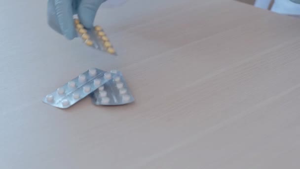 Mann in medizinischen Gummihandschuhen legt Tabletten, Spritze und Impfflasche auf den Tisch. — Stockvideo