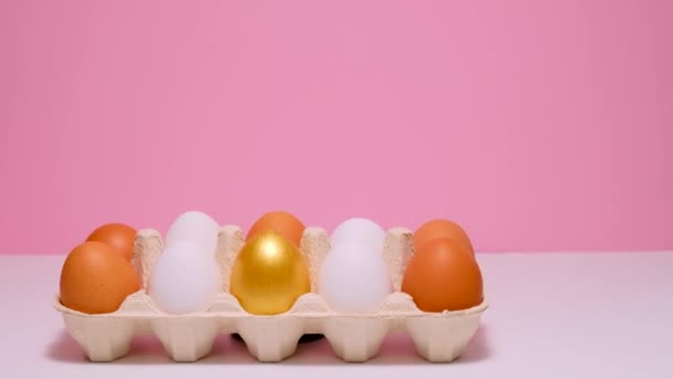 Œufs de Pâques colorés dans une boîte en carton. Œufs colorés sur un fond rose. — Video